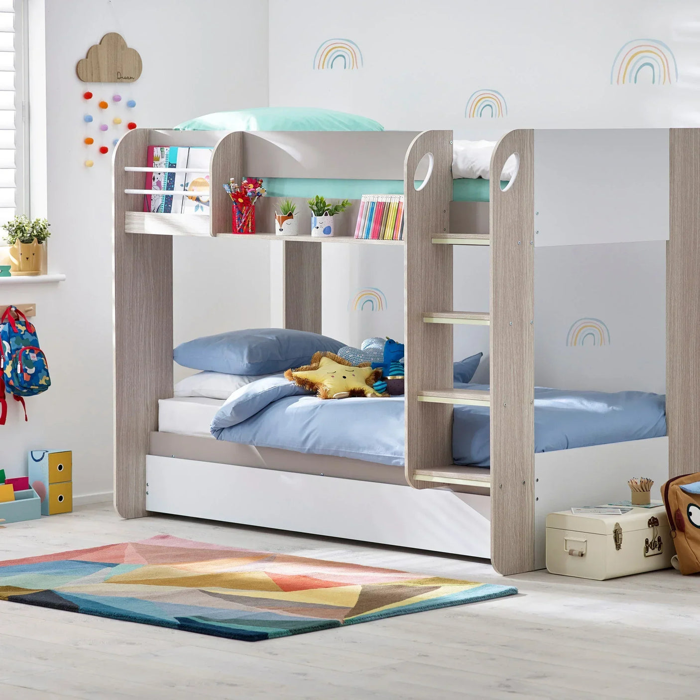 Wooden bunk bed with ladder, blue bedding, storage drawer, kids’ room decor and rainbow wall decals