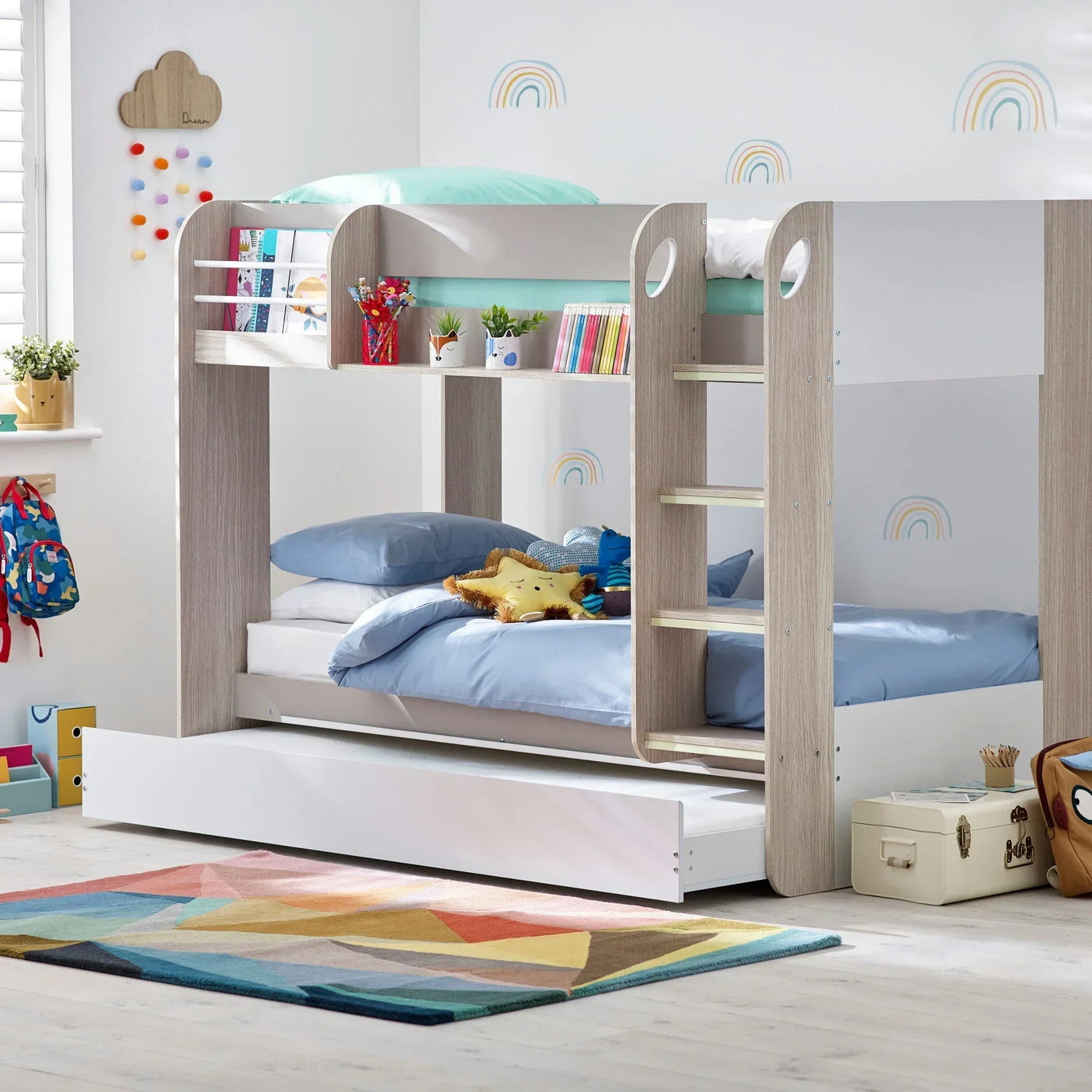 Children’s bunk bed with light wood frame, ladder, bookshelves and blue bedding in kids room