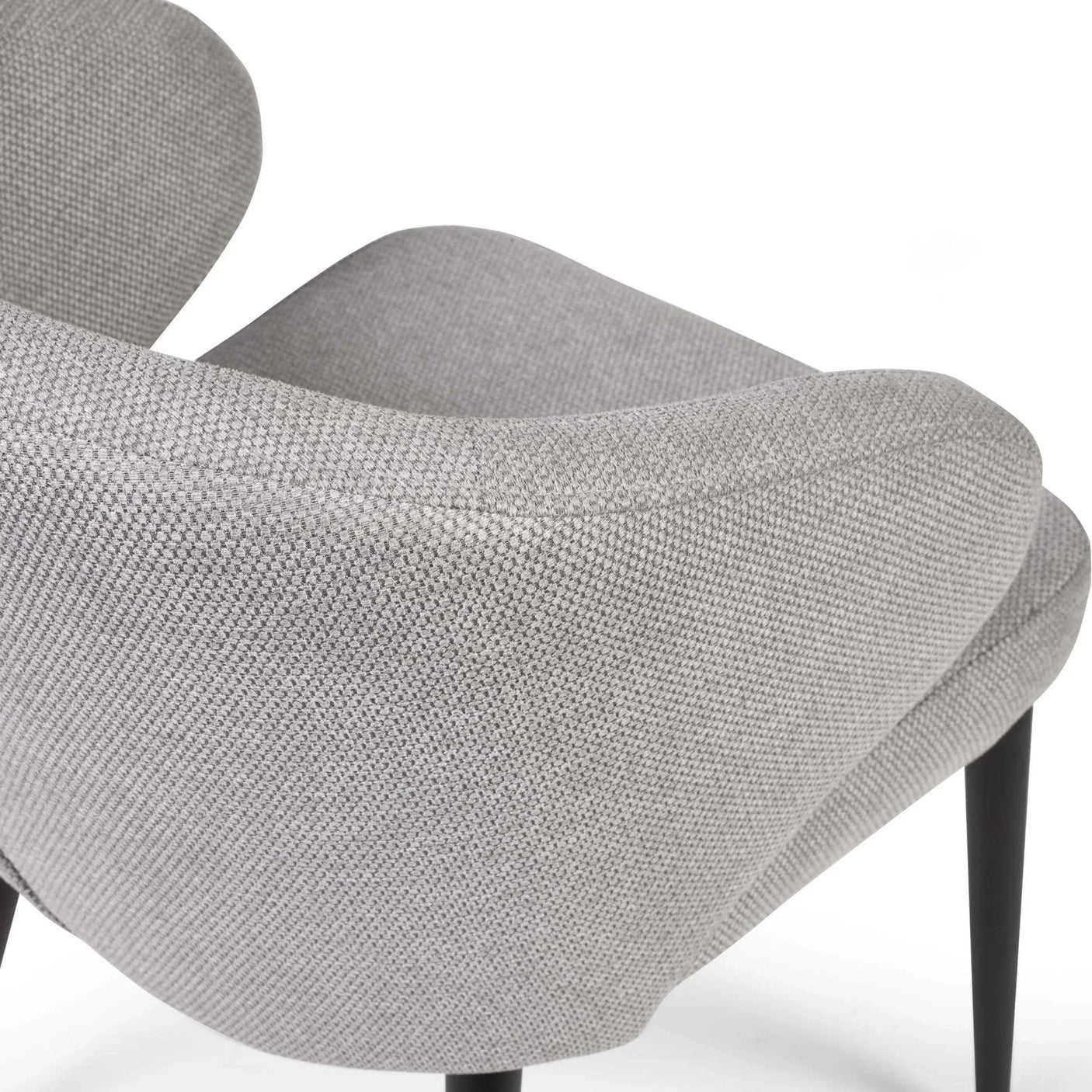 Close-up of grey fabric armchair with curved backrest and black tapered legs