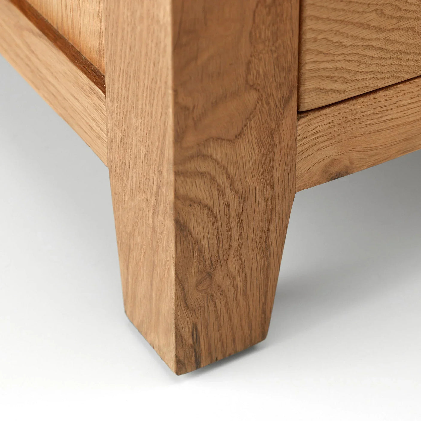 Solid oak furniture leg close-up showing natural wood grain and angled design