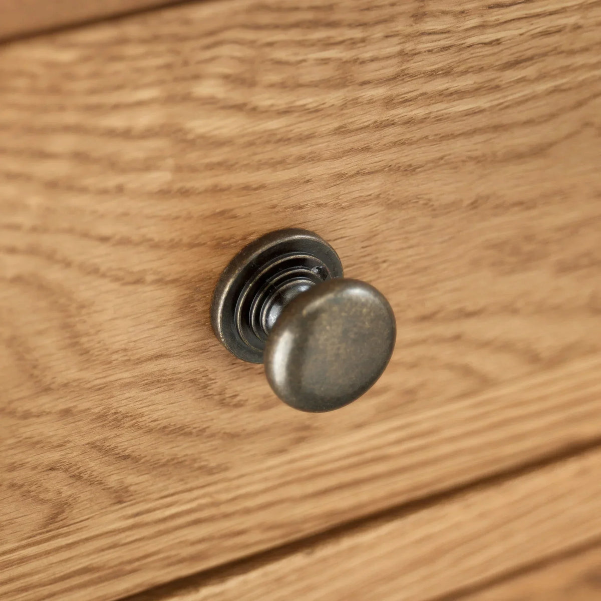 Metal drawer handle on light oak wood chest closeup