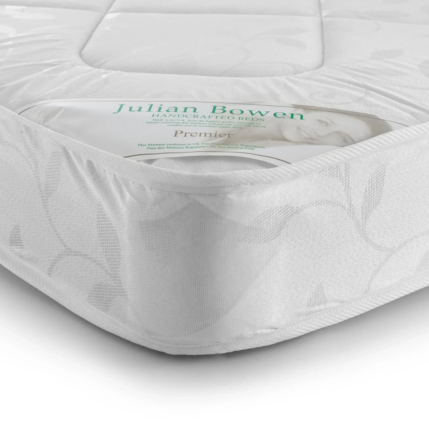 Closeup of Premier 135cm mattress corner with white patterned fabric and product label visible