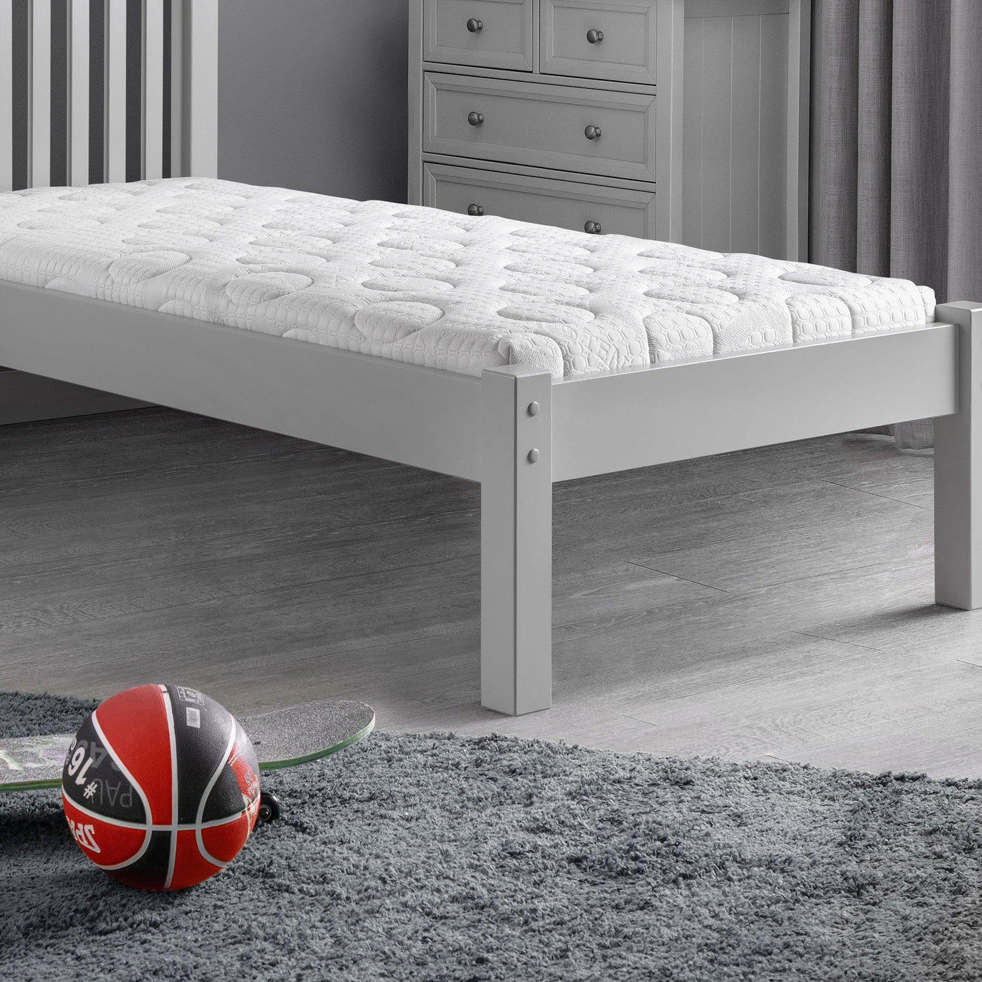 Single reflex roll-up mattress on white wooden bed frame in modern grey bedroom