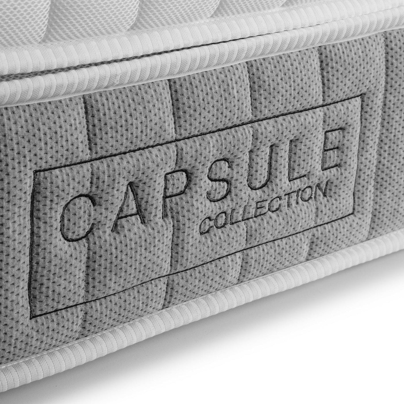 Closeup of Capsule Collection mattress side panel with grey fabric and stitched logo detail