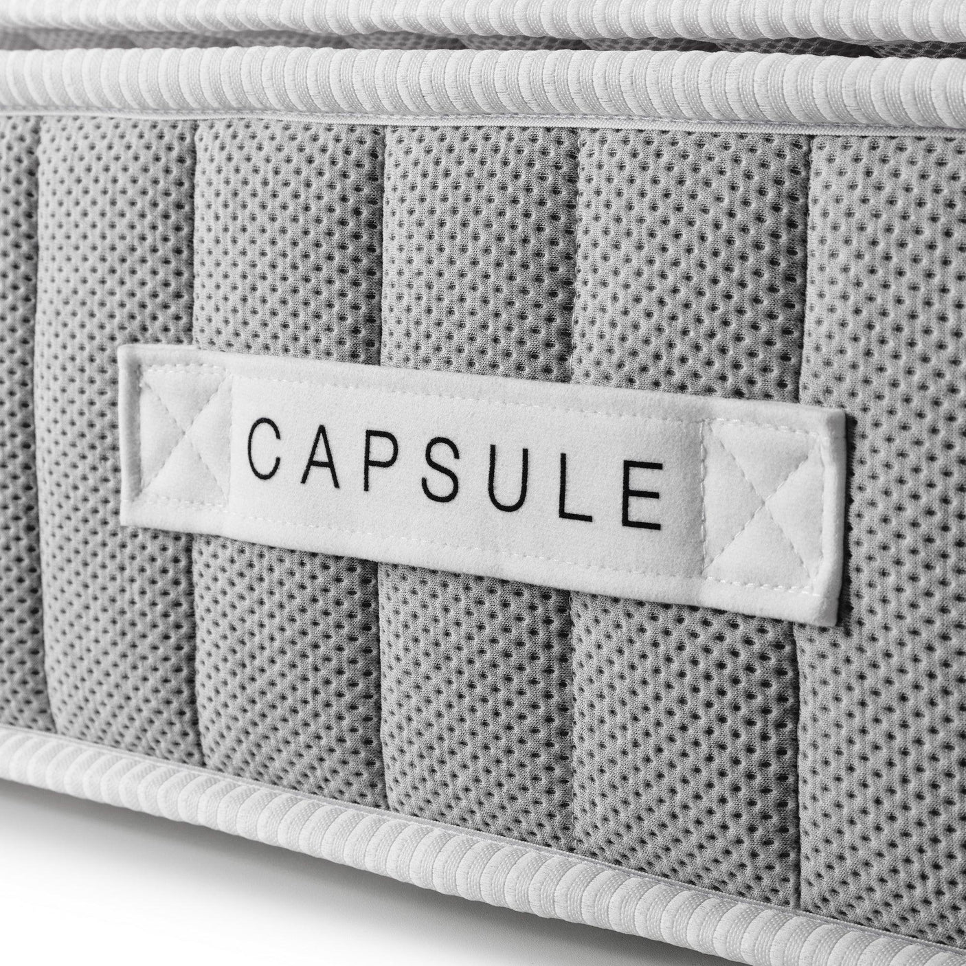 Closeup of grey Capsule mattress with textured fabric and stitched side label detail