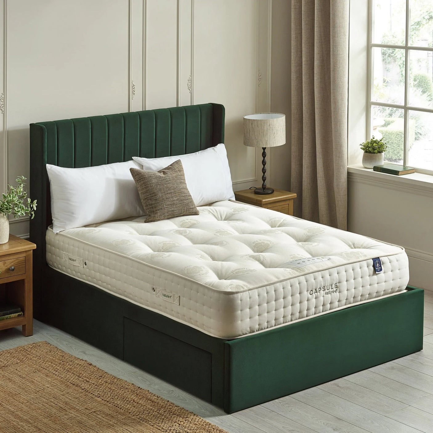 Luxury pocket sprung mattress on green upholstered bed frame beside wooden nightstands