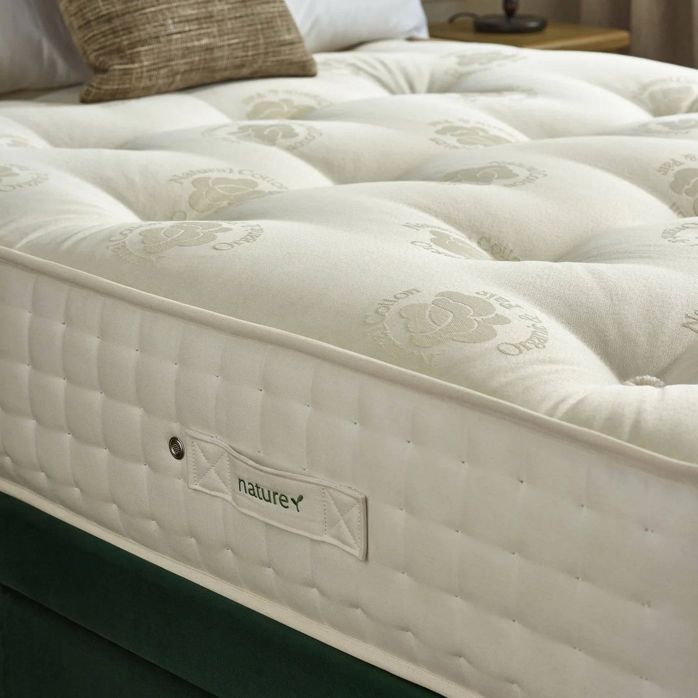 Natural cotton mattress with quilted sides and label on upholstered bed base