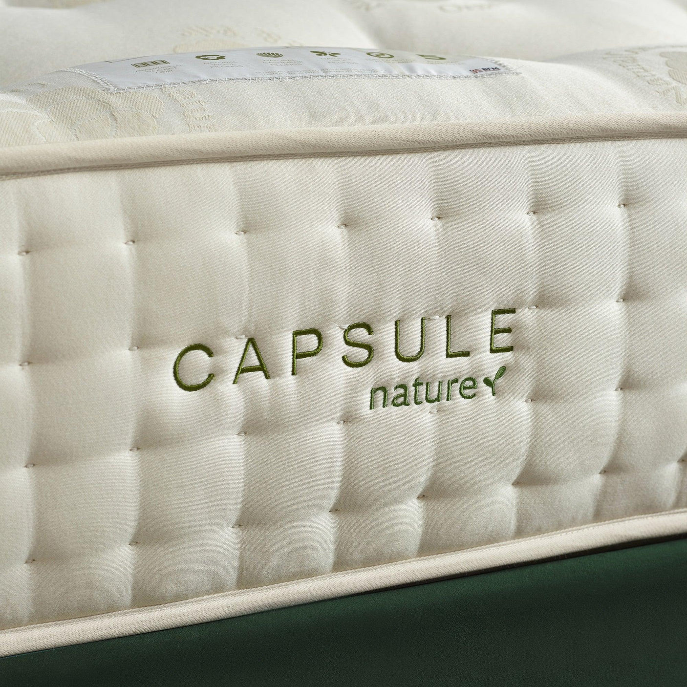 Closeup of Capsule Nature mattress corner with quilted fabric and stitched green logo