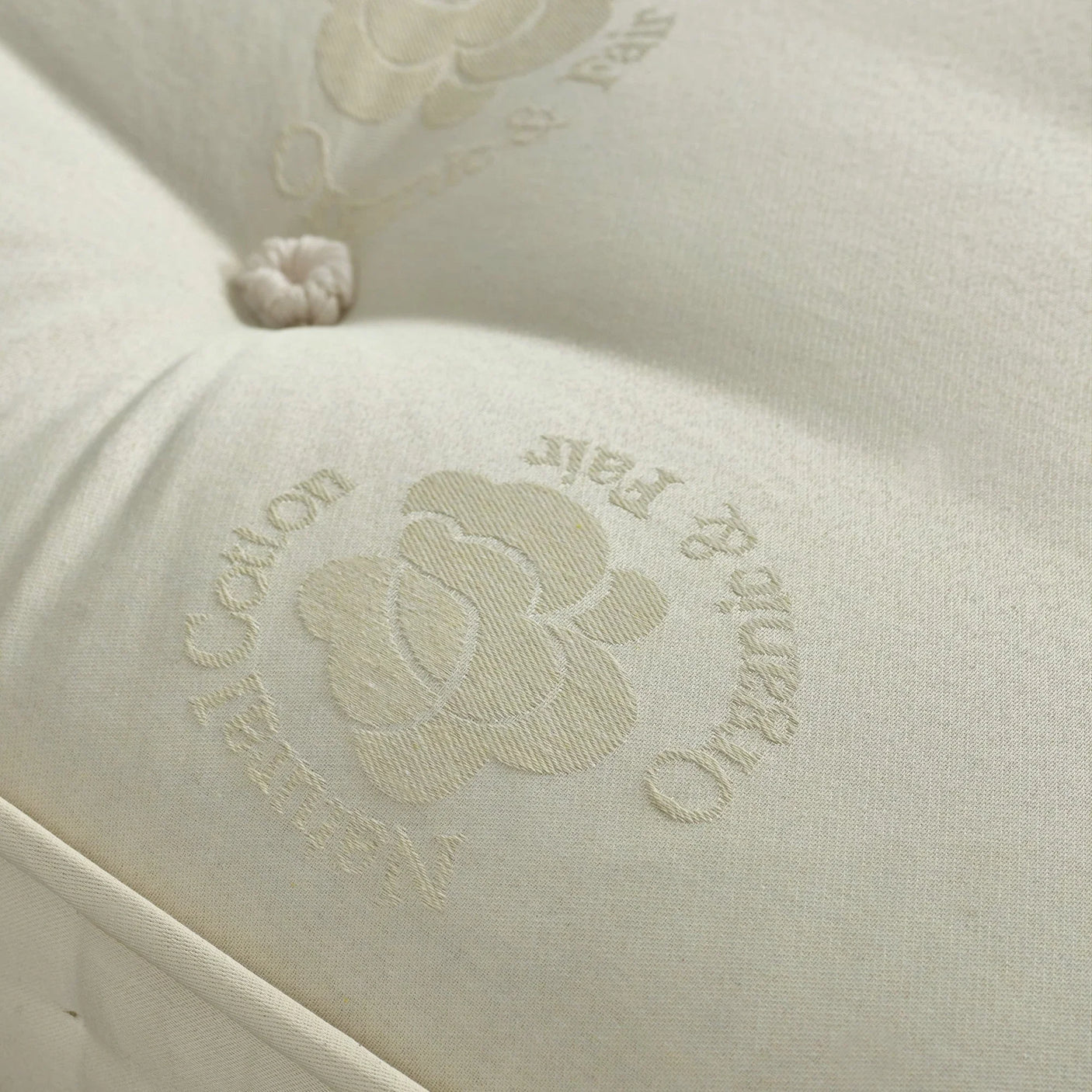 Natural cotton mattress surface with tufted button and floral embroidery detail