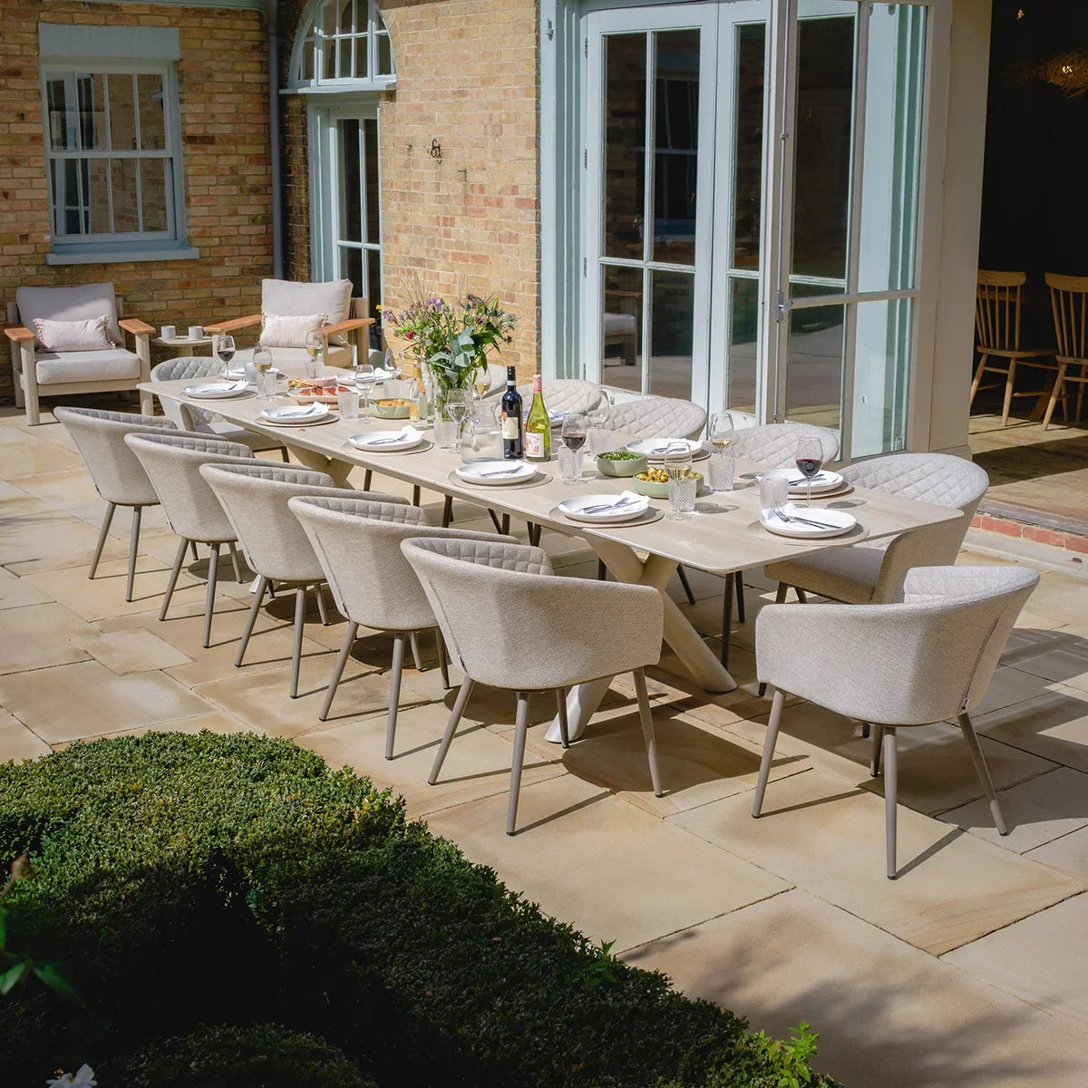 Large outdoor dining set with beige cushioned chairs and rectangular table on patio