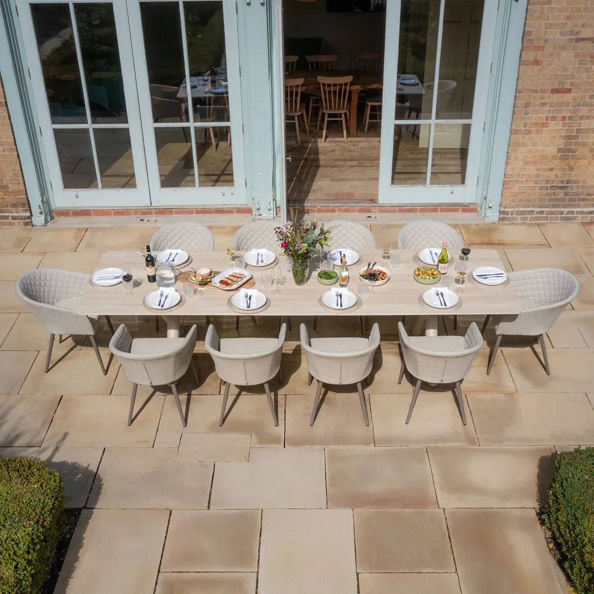 Large outdoor dining set with beige cushioned chairs and long rectangular table set for eight