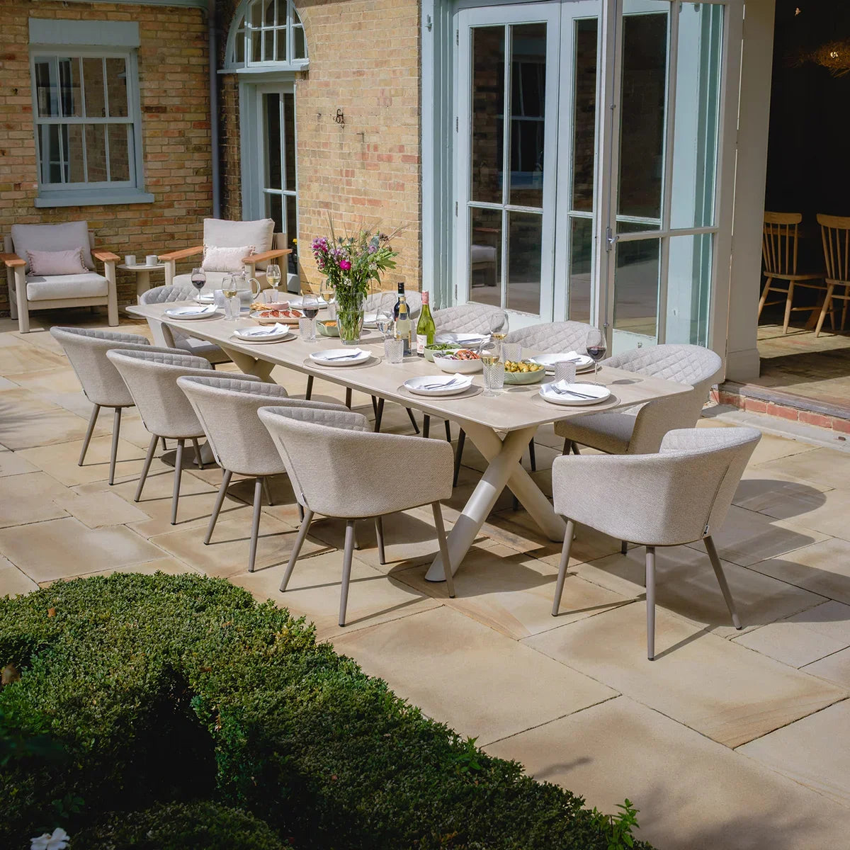 Modern outdoor dining set with eight cushioned chairs and rectangular table on stone patio