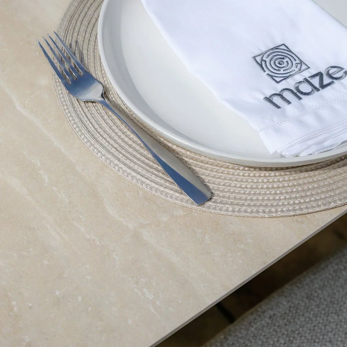 Light beige ceramic dining table top with white plate, napkin and stainless steel fork