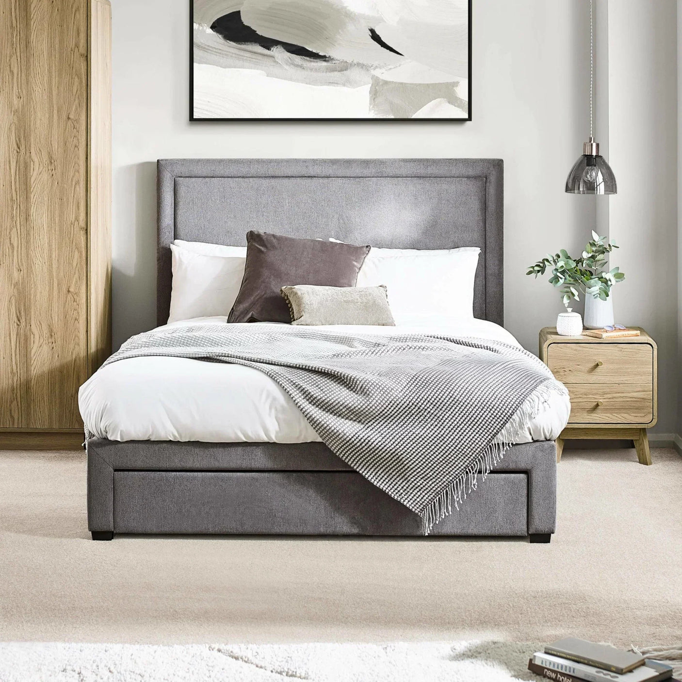 Grey upholstered bed with storage, white bedding and throw in modern bedroom setting