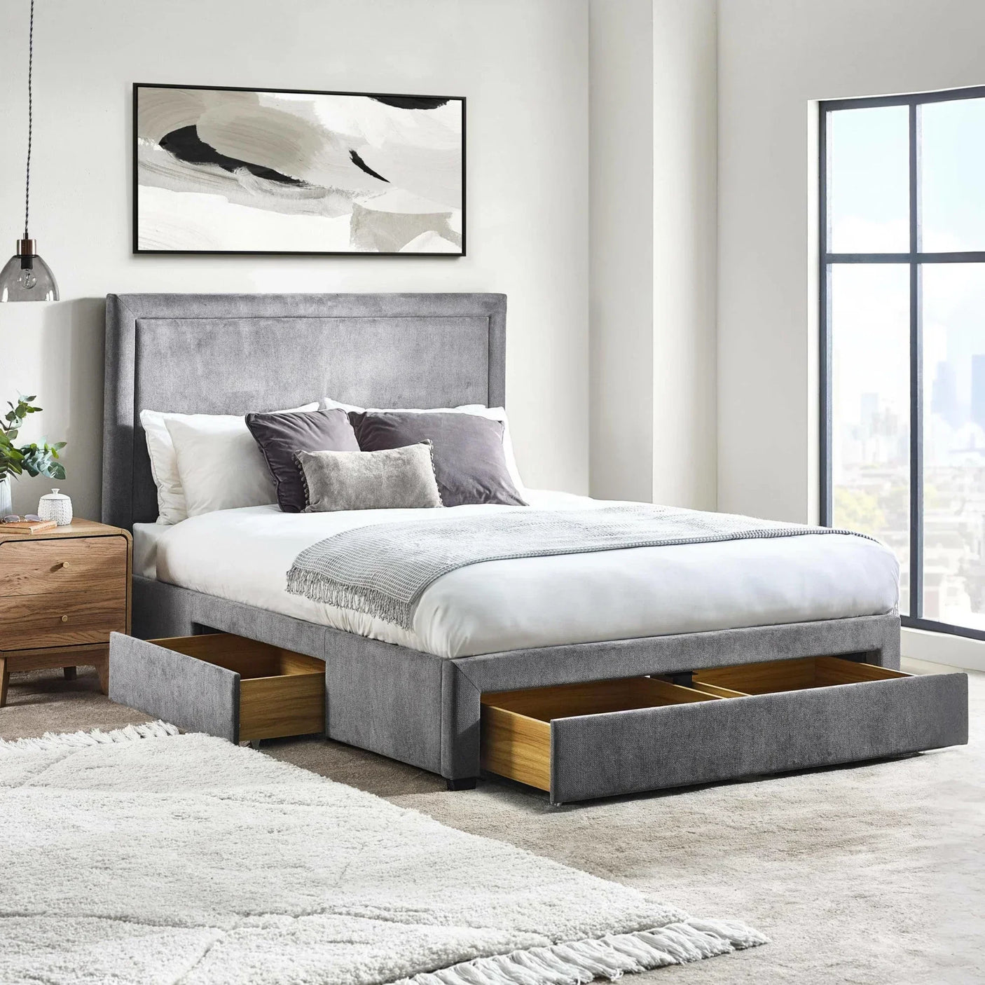 Grey upholstered storage bed with open drawers in bright modern bedroom