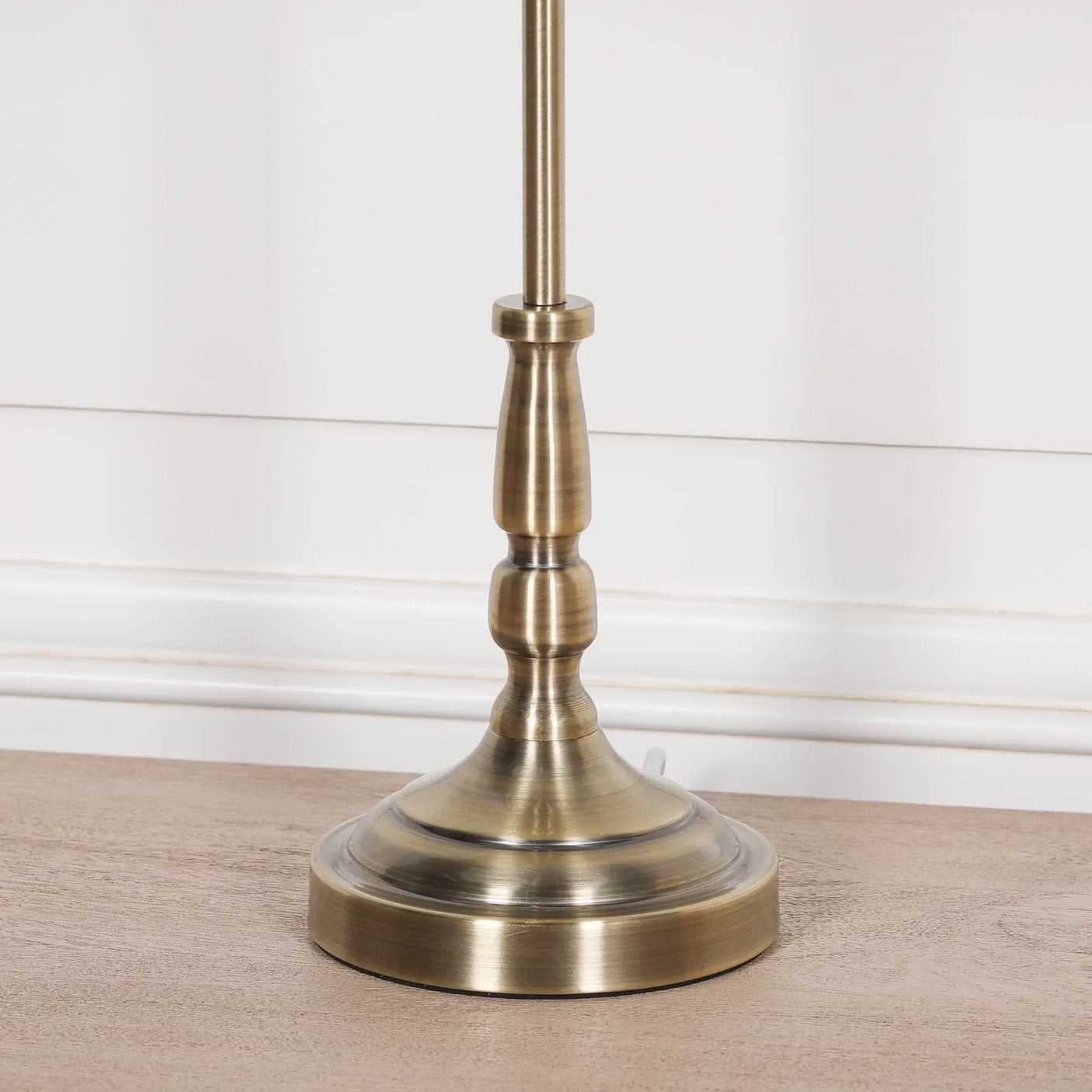 Brushed brass table lamp base with turned detailing on wood surface