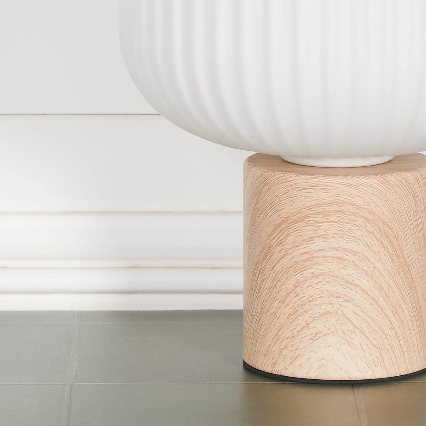 Ceramic planter with ribbed white finish on a light wood base, closeup floor view