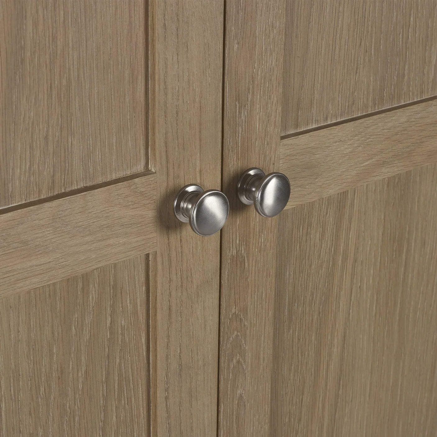Close view of limed oak wardrobe doors with silver handles and wood grain texture