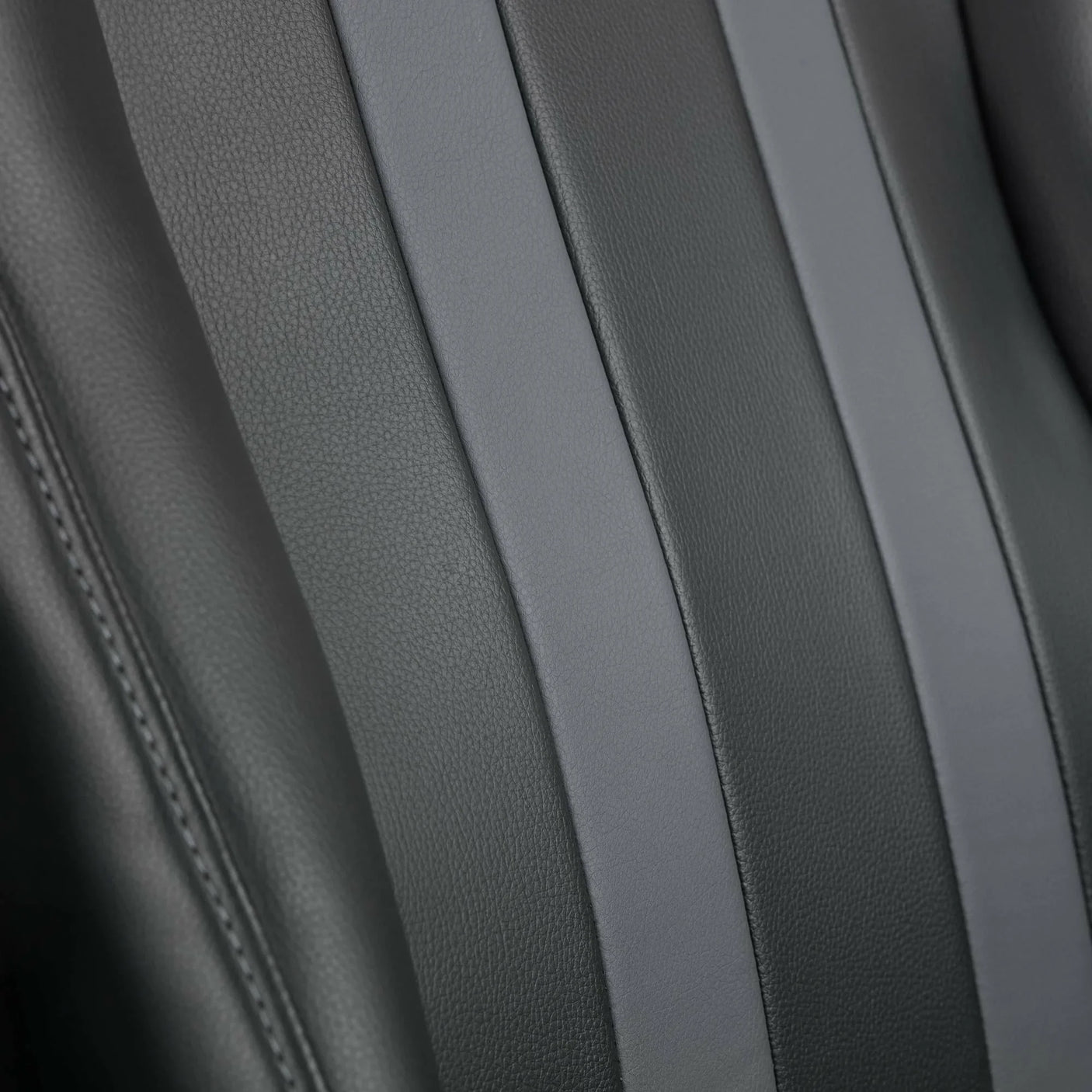 Closeup of grey faux leather gaming chair backrest with textured panels and stitched detail