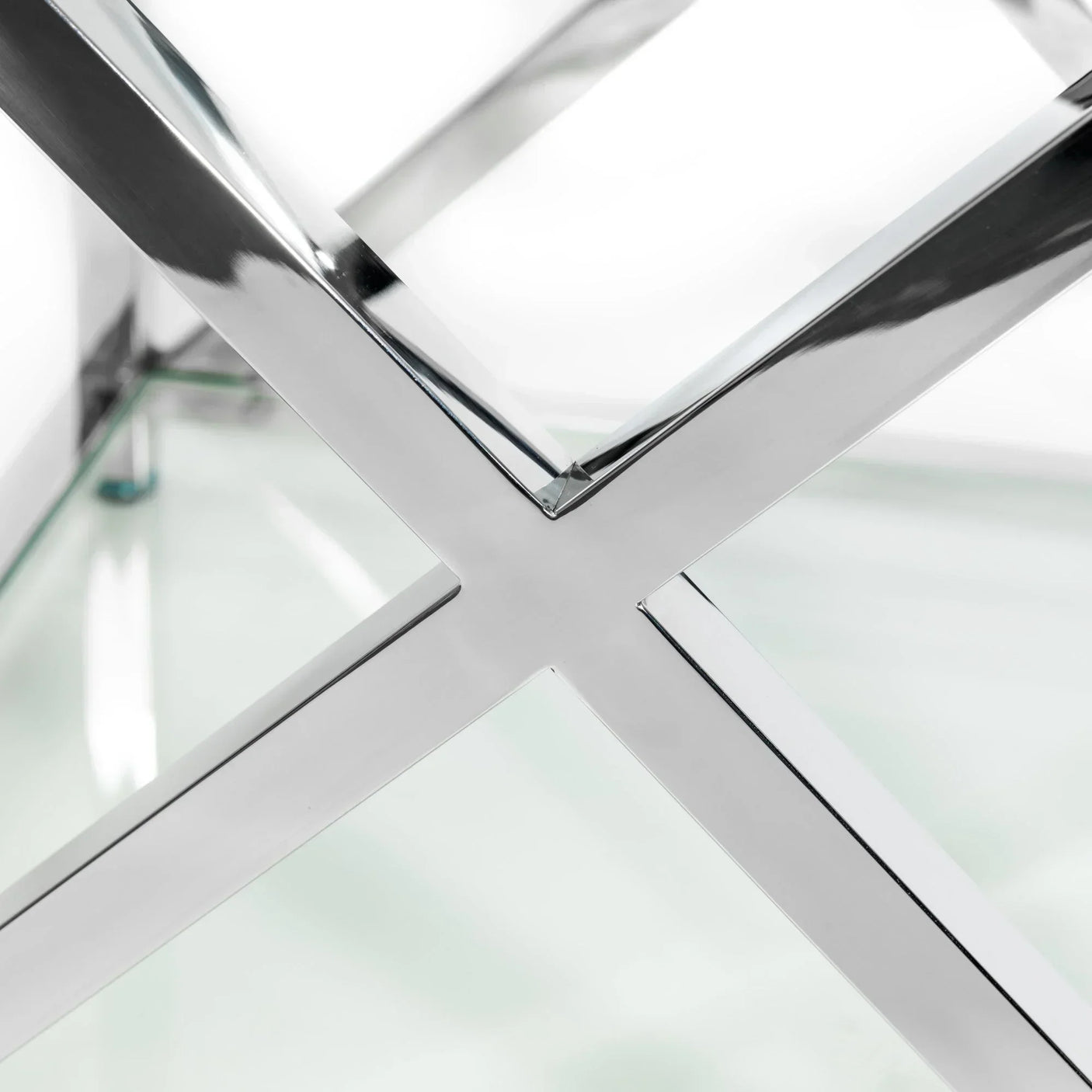 Close-up of glass table top with chrome metal cross frame detail