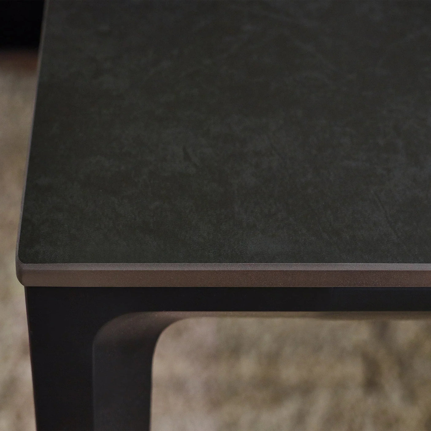 Close-up of rectangular stone dining table top with dark finish and metal frame