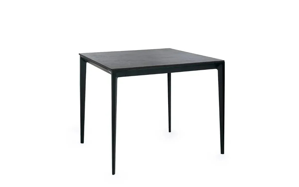 Black square dining table with slim legs, modern finish, shown at an angle