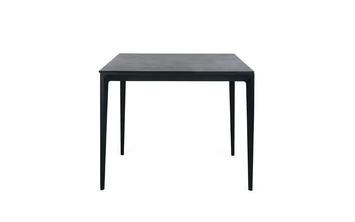 Black square dining table with slim tapered legs and minimalist design, front view