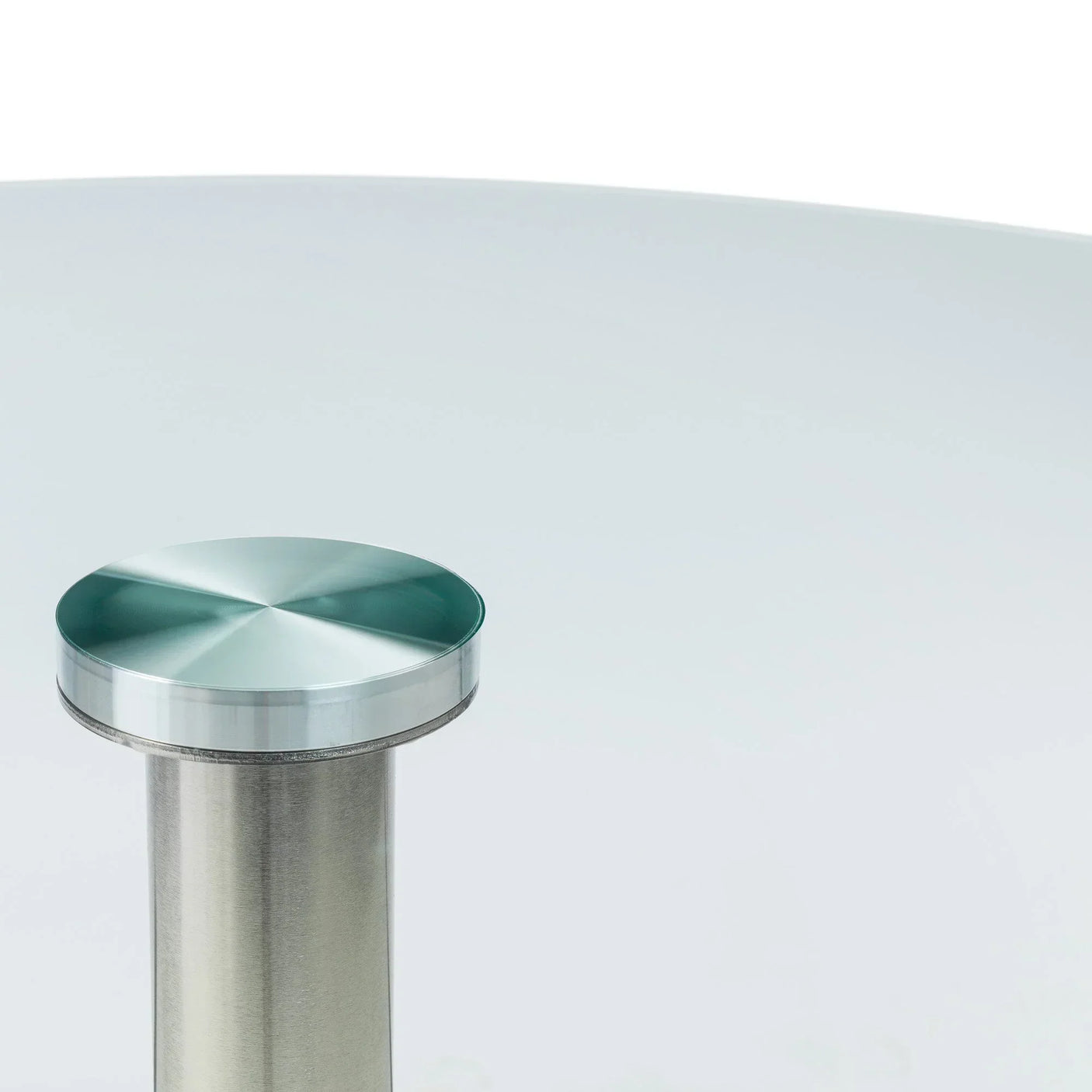 Close up of round glass table top with brushed stainless steel leg and fixing detail