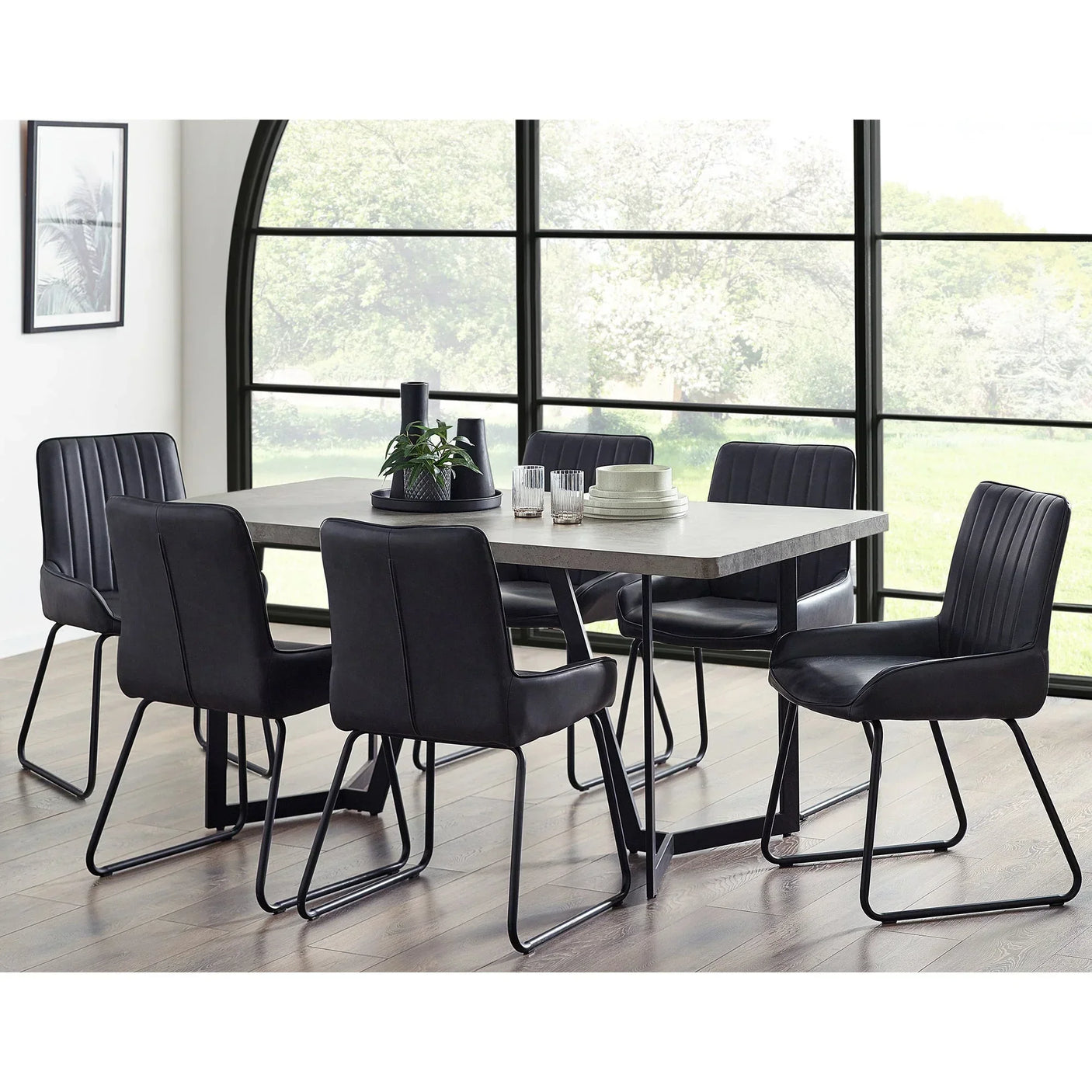 Concrete effect dining table with six black leather chairs in a modern dining room