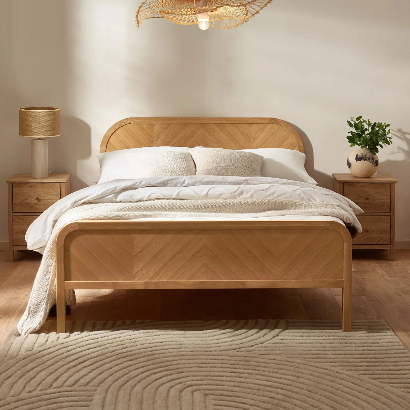 Oak wood bed frame with herringbone pattern, white bedding, two bedside tables, neutral decor