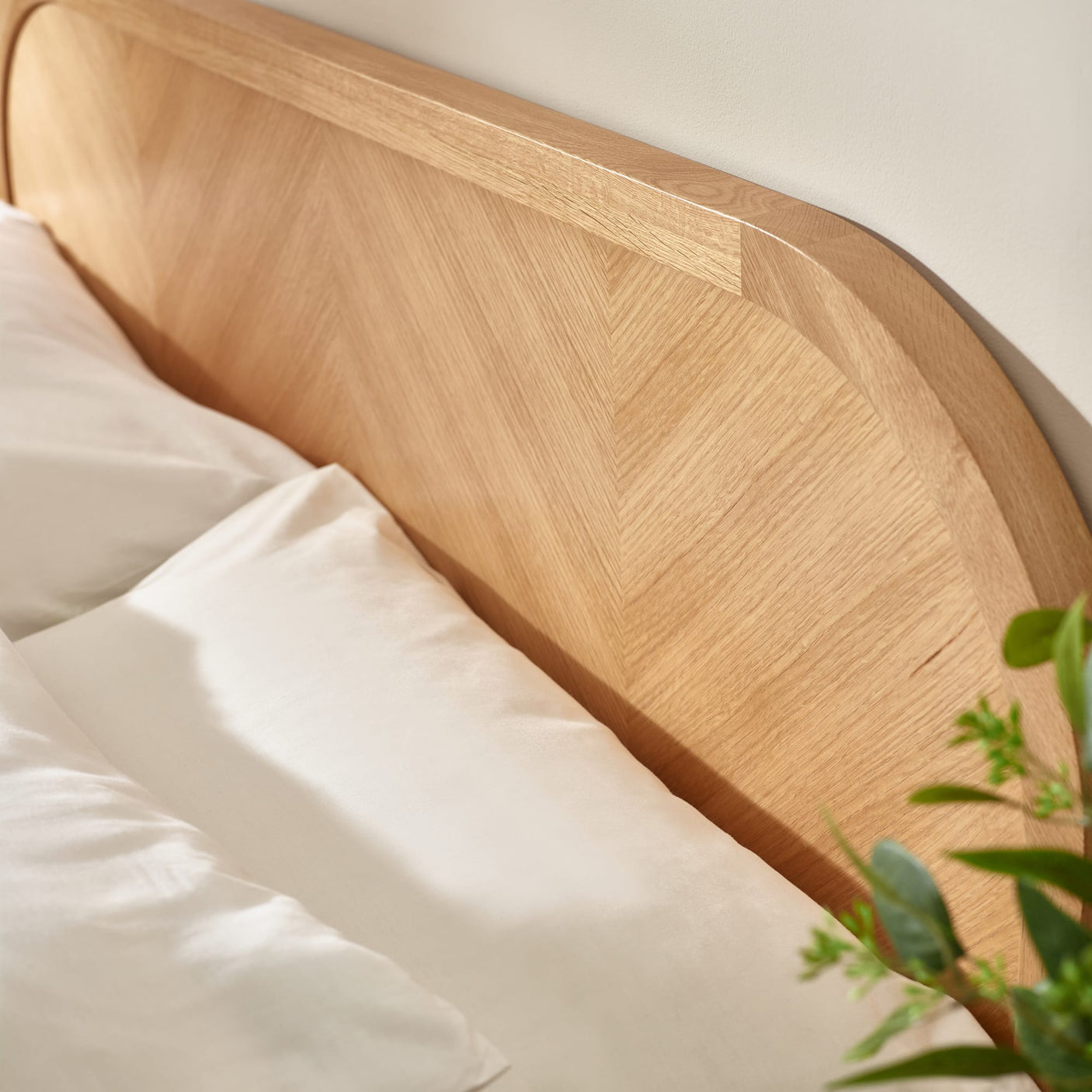 Close-up of chevron-pattern oak headboard top edge and pillow