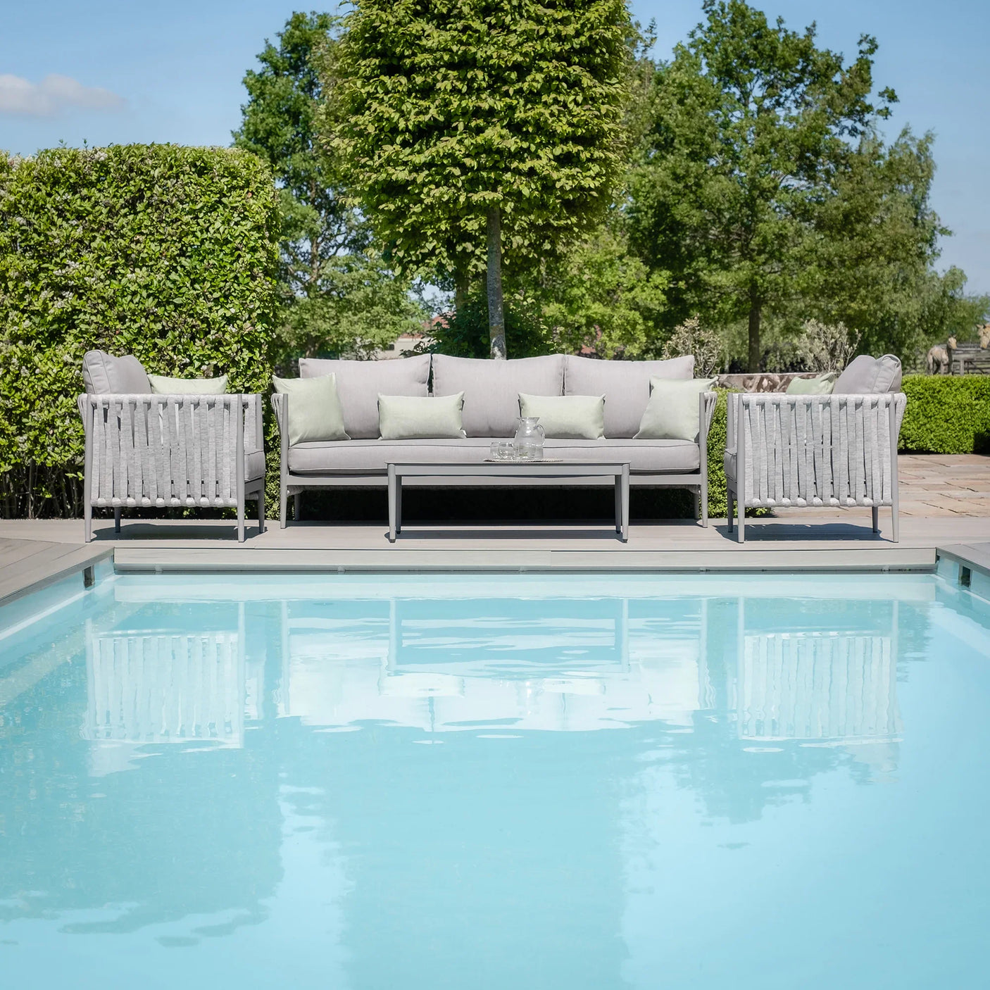 Grey outdoor sofa set with coffee table beside swimming pool in garden setting