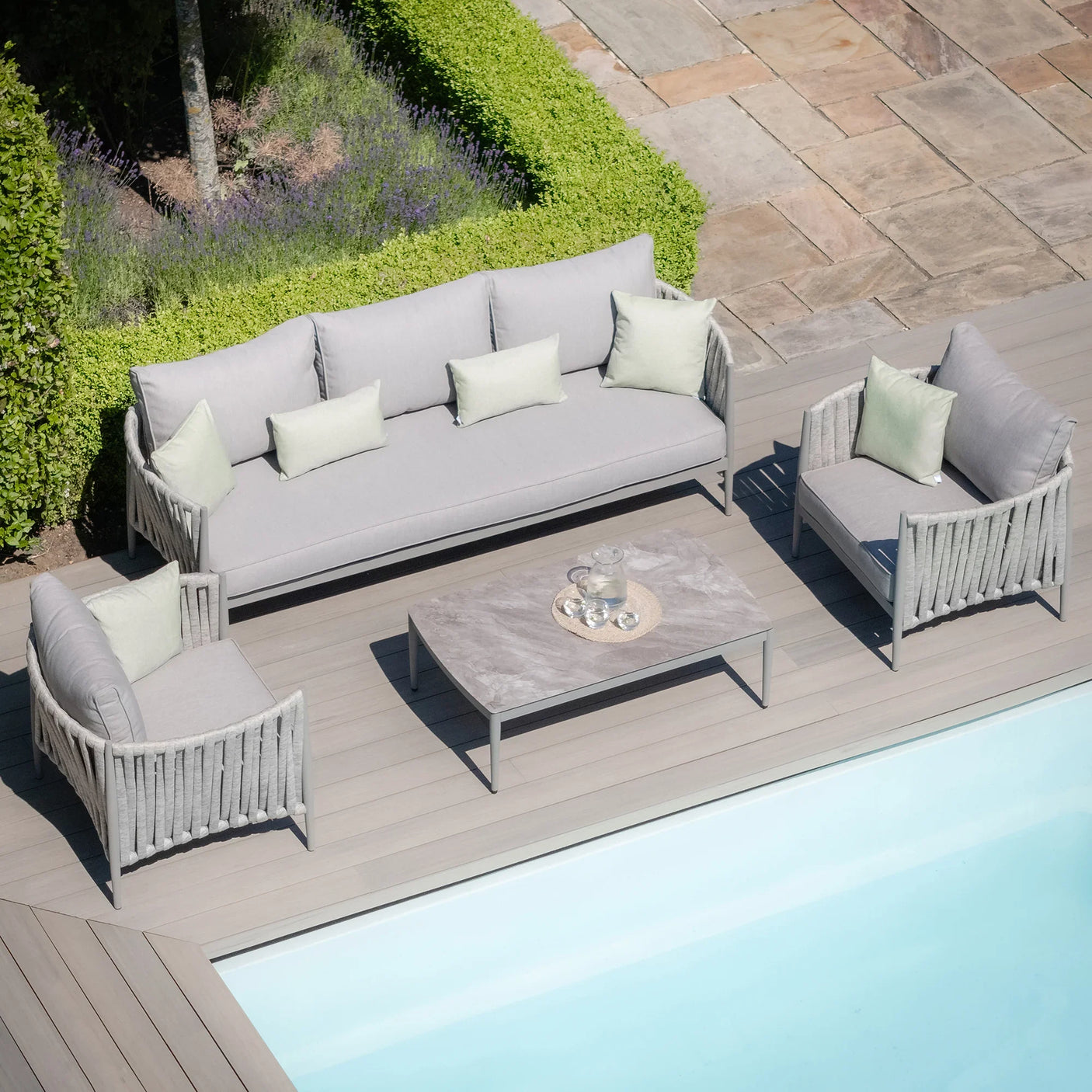 Grey outdoor sofa set with coffee table and cushions on poolside patio