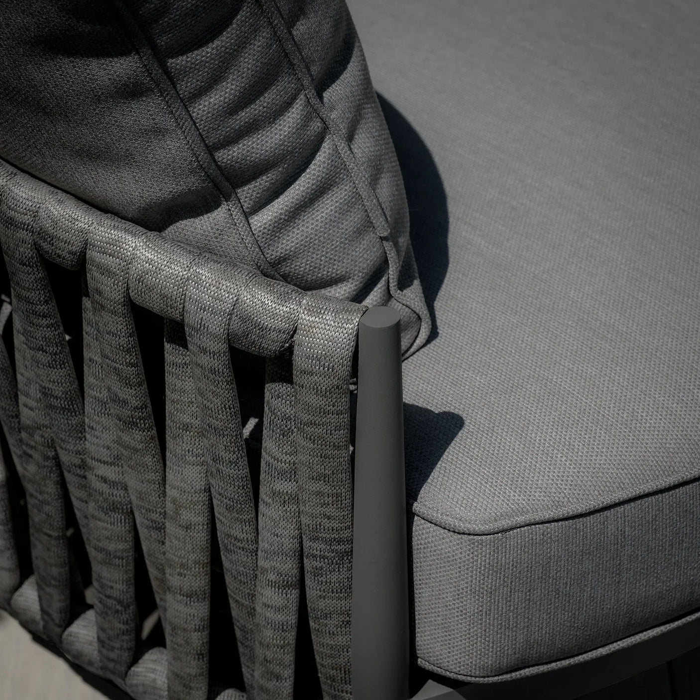 Close up of grey outdoor chair with woven rope backrest and textured seat cushion