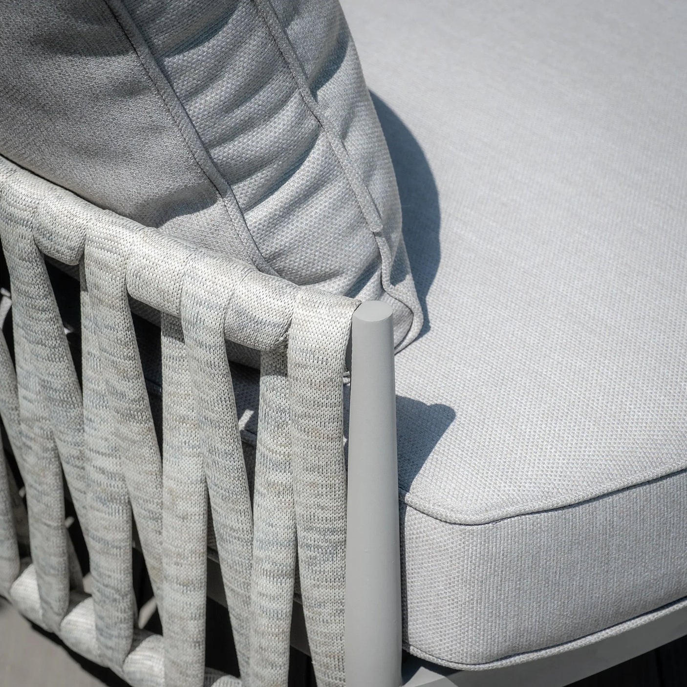 Closeup of woven rope outdoor sofa armrest with light grey cushion and pillow detail