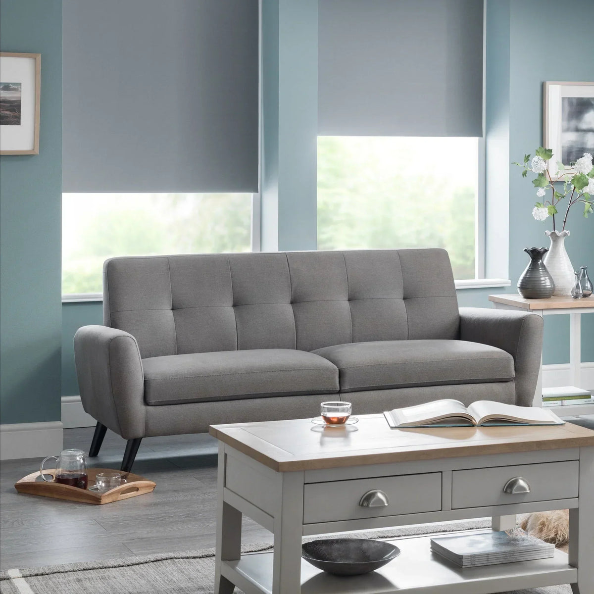 Grey fabric sofa with wooden legs in modern living room next to coffee table and side table