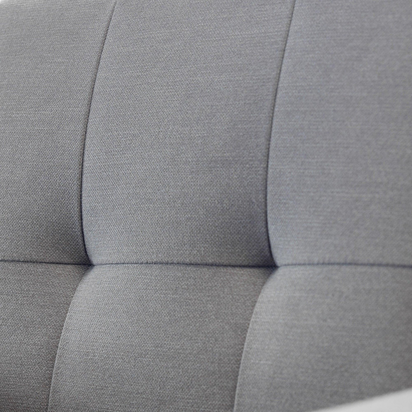 Close-up of grey fabric sofabed backrest with stitched panel detail