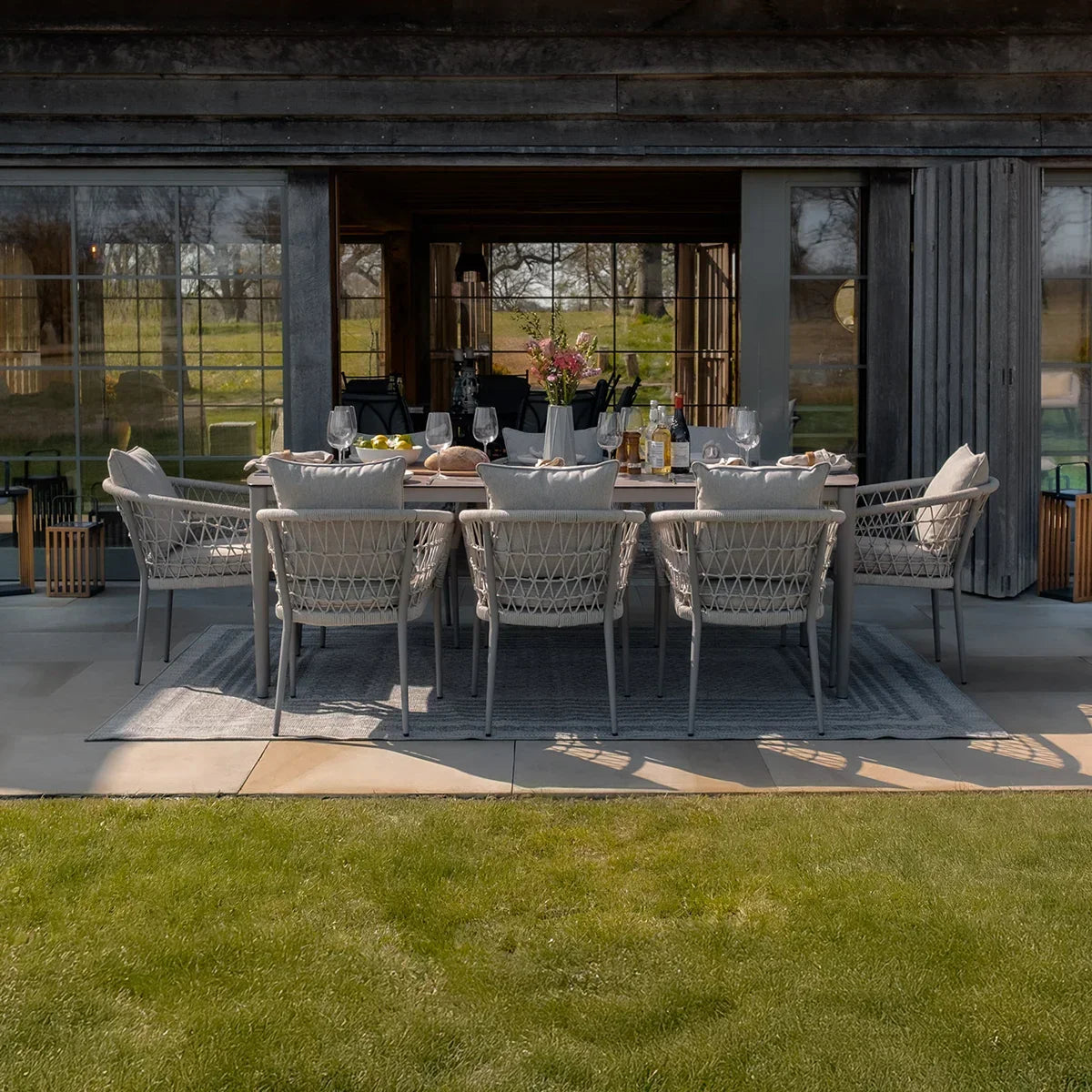Outdoor rattan dining set with eight cushioned chairs and rectangular table on patio
