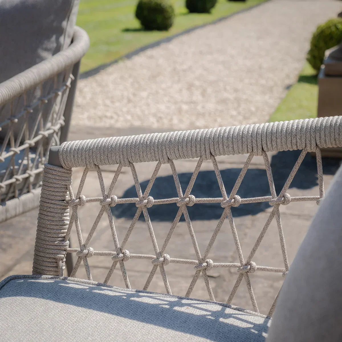 Close-up of outdoor sofa with woven rope detailing on armrest and light grey cushion