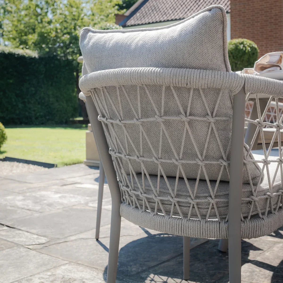 Close-up of grey woven rope outdoor dining chair with cushion on patio