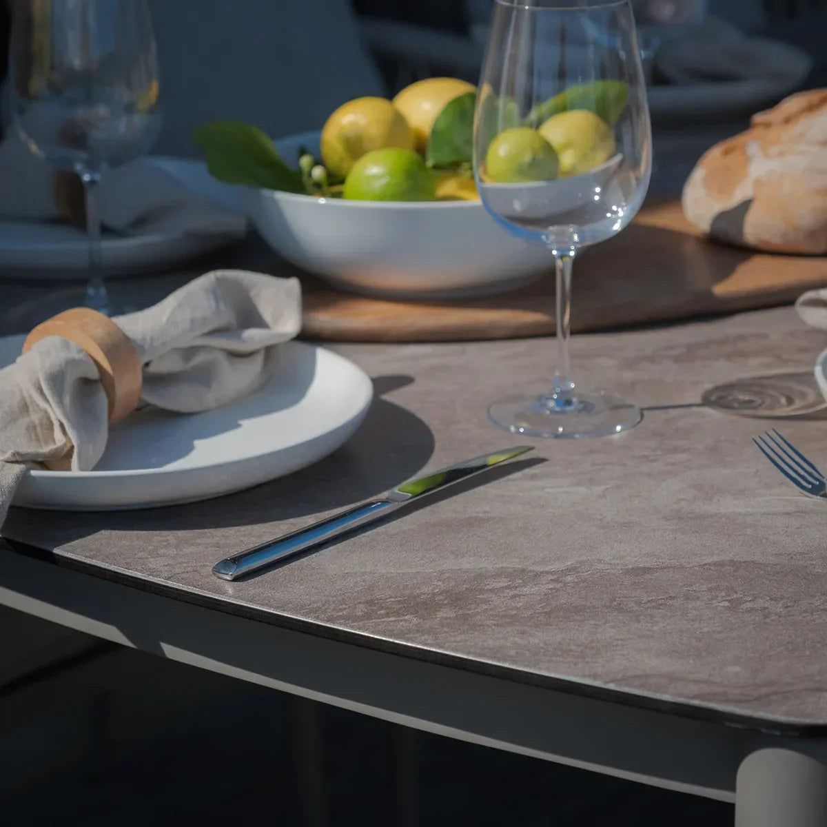 Stone effect dining table with place settings, glassware, and bowl of fresh lemons and limes