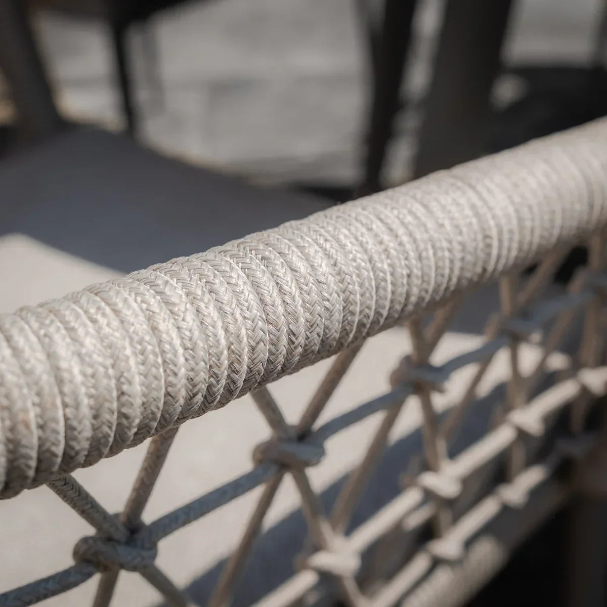 Close-up of beige woven rope detail on outdoor sofa armrest