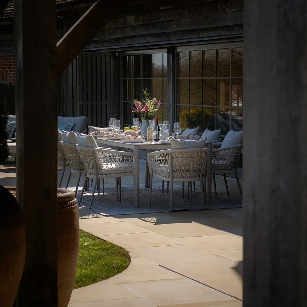 Outdoor dining set with woven chairs and grey table arranged on patio with tableware