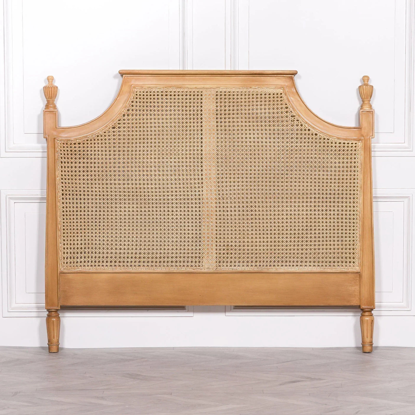 Natural wood rattan headboard with woven cane panel and carved finials against white wall