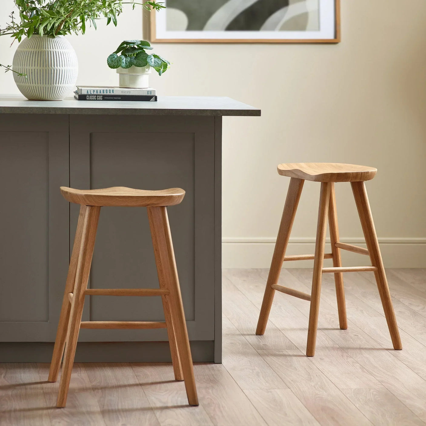Pair of wooden kitchen bar stools with contoured seats by a modern island