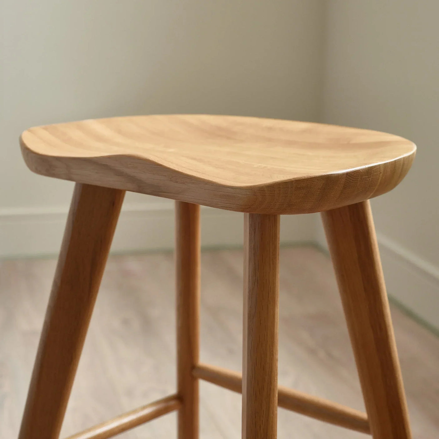 Solid wood bar stool with contoured seat in natural finish, close-up on legs and seat