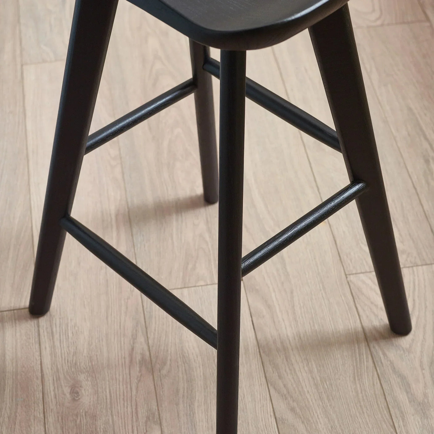 Black wooden bar stool legs on light oak floor