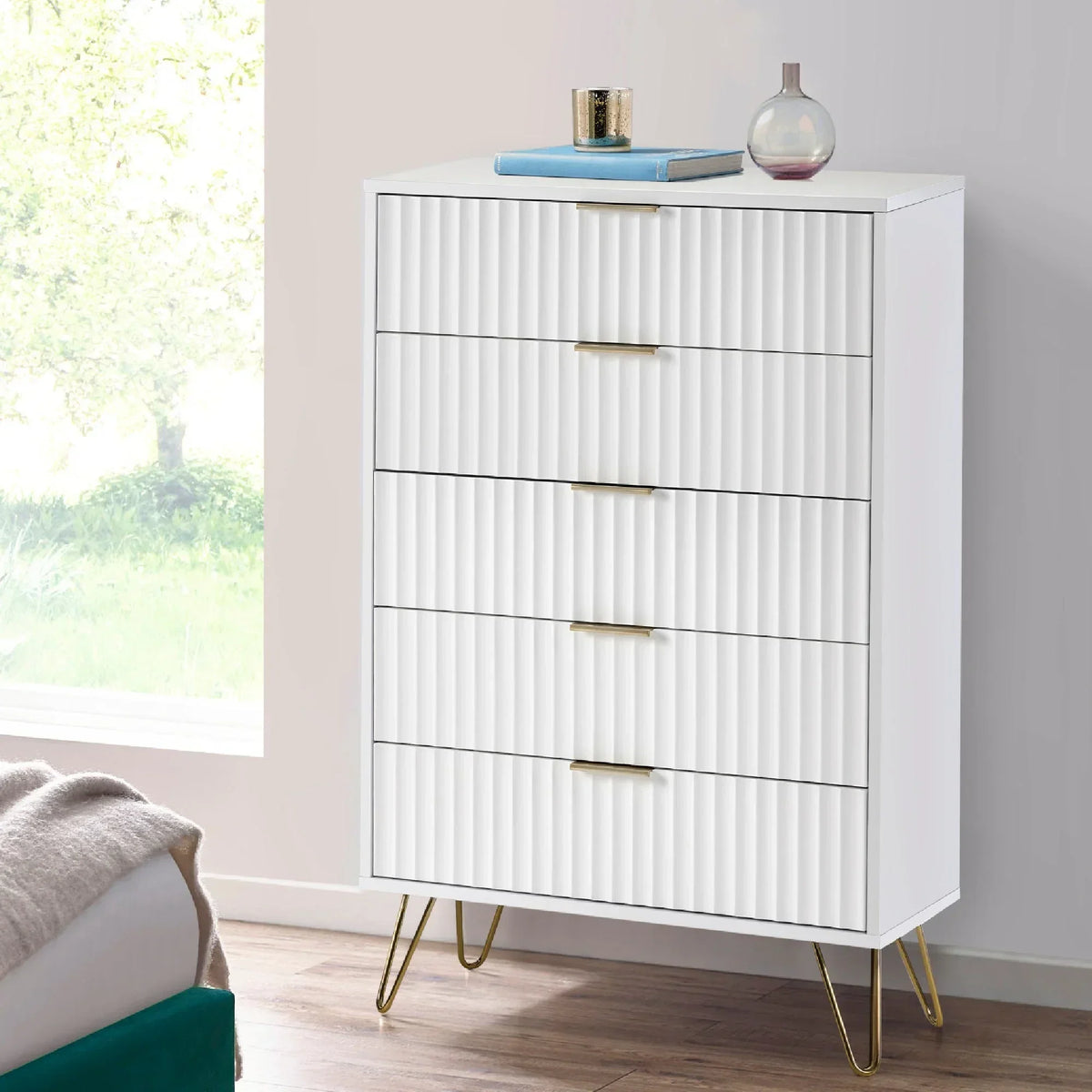 White chest of drawers with gold handles and legs, ribbed front detail in modern bedroom
