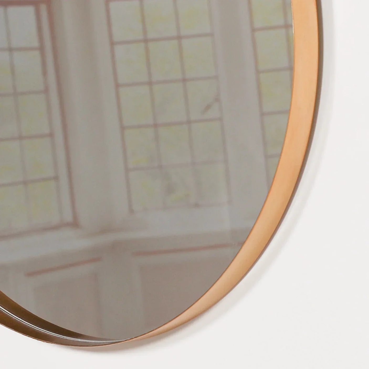Closeup of round wall mirror with gold metal frame reflecting window