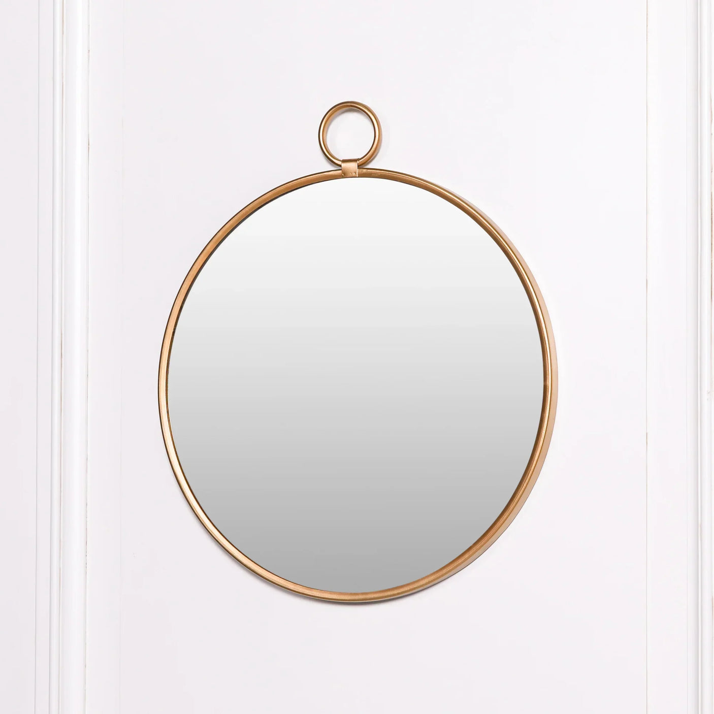 Round wall mirror with gold metal frame and hanging loop on white background